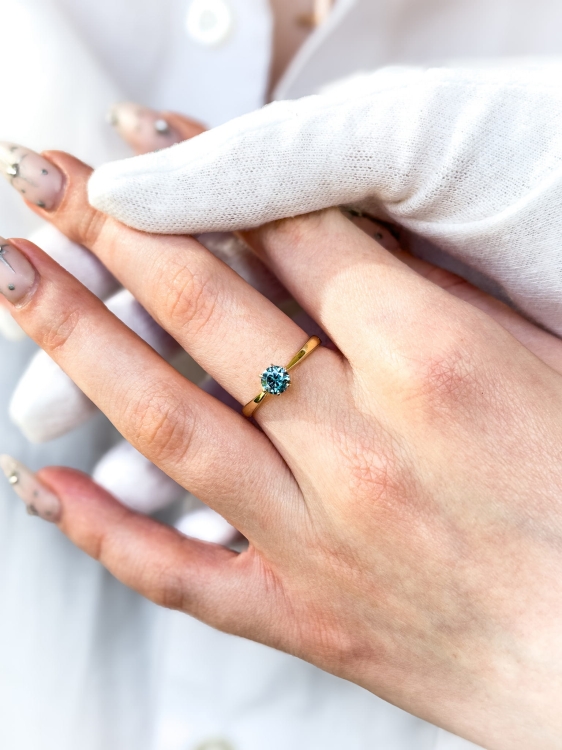 Pierścionek zaręczynowy z żółtego złota próba 585 z niebieskim moissanitem 0,50 ct – na dłoni – ABGOLD Baczyński